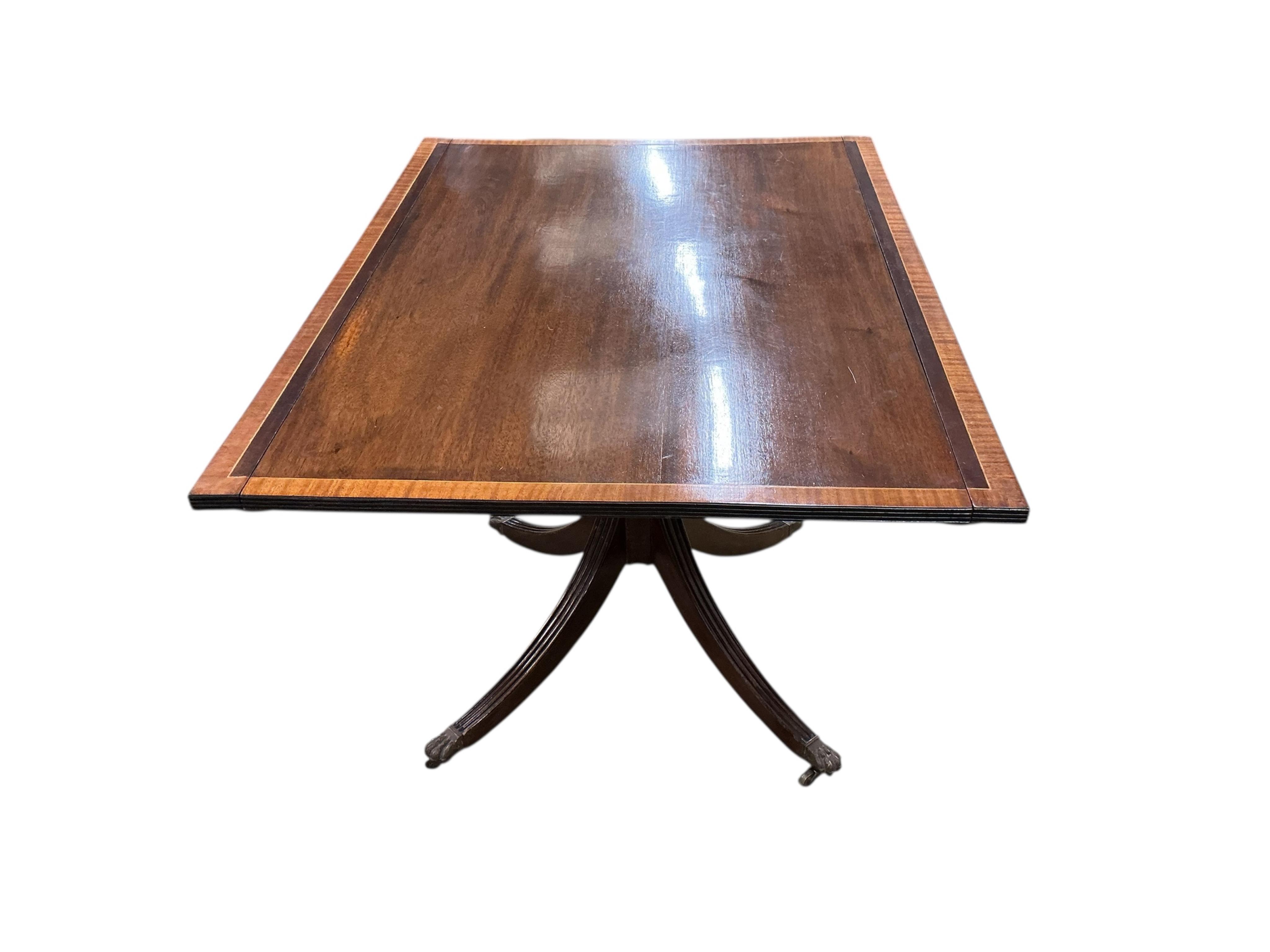 A Regency style mahogany and satinwood banded three pillar dining table, width 320cm extended, two spare leaves, depth 114cm, height 74cm